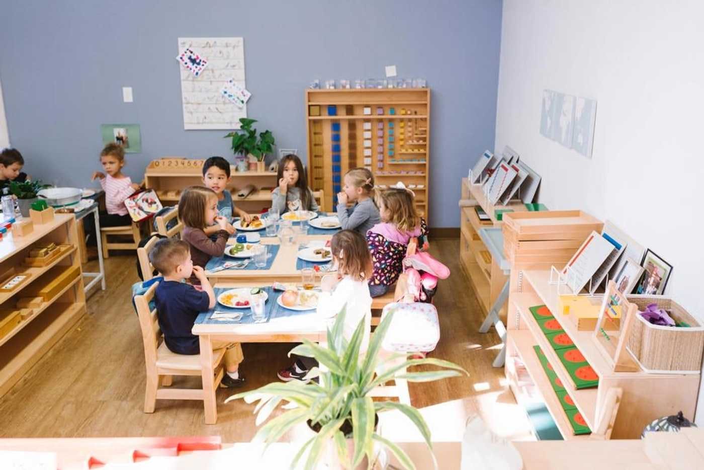 children sitting at tables in a guidepost montessori classroom eating