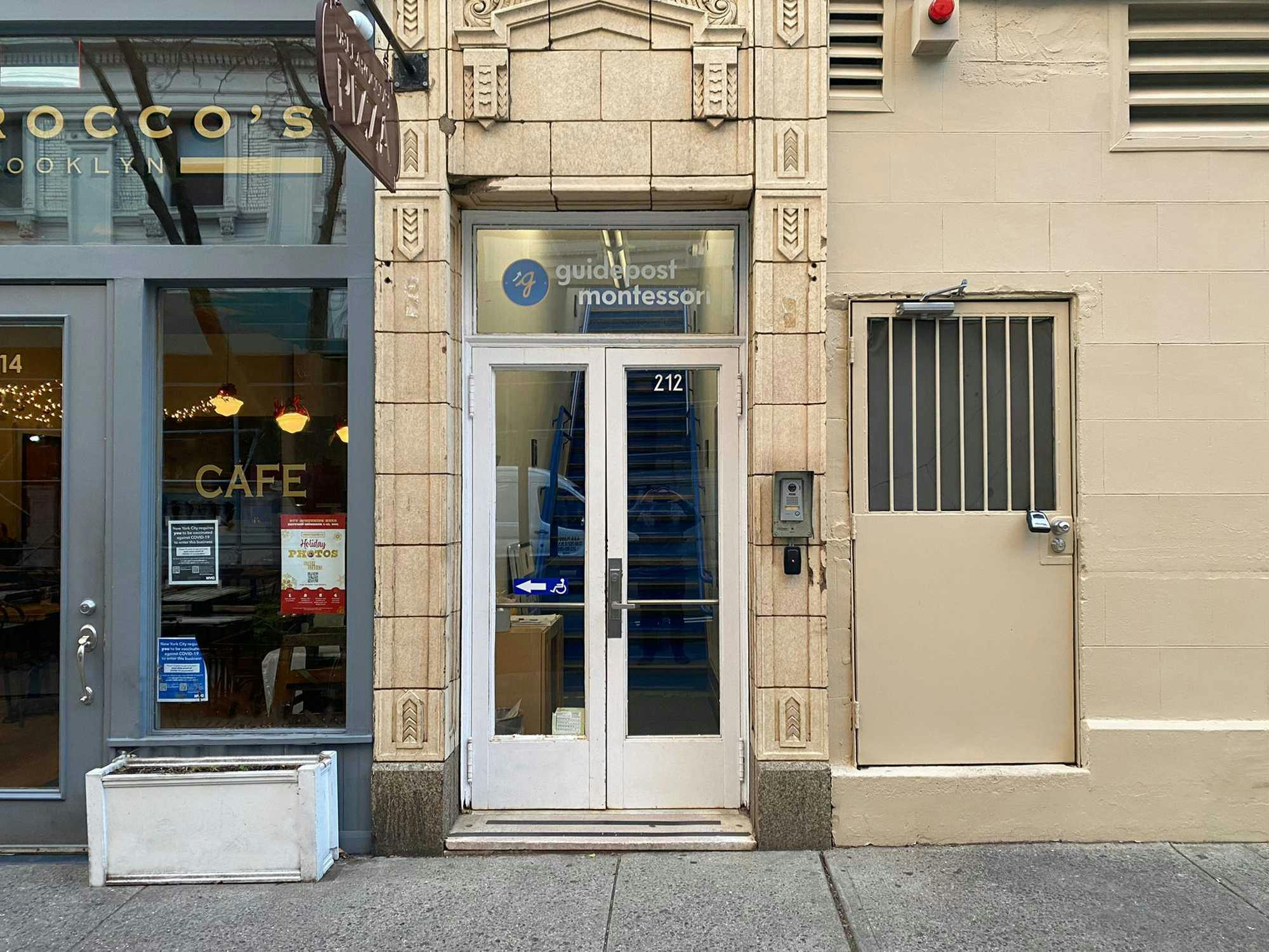 View of the entrance to Guidepost Montessori at Brooklyn Heights that shows the front entrance with a branded Guided Montessori sign and the cafe entrance next door.