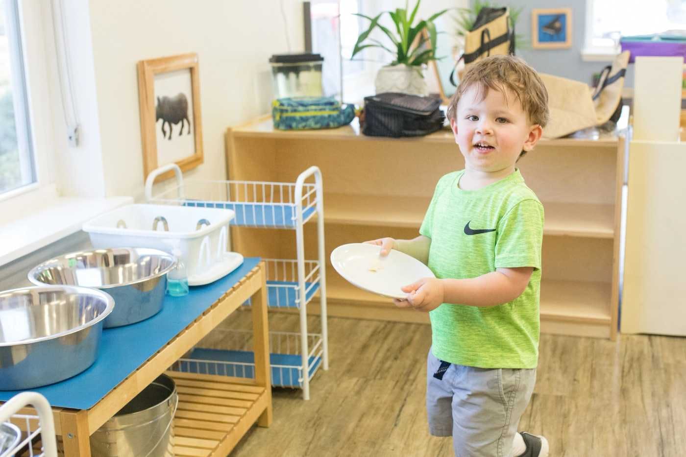 child at guidepost montessori holding a plate to clean