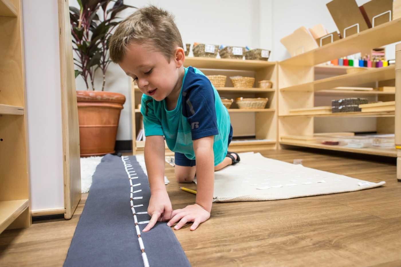 child at guidepost montessori counting on the floor