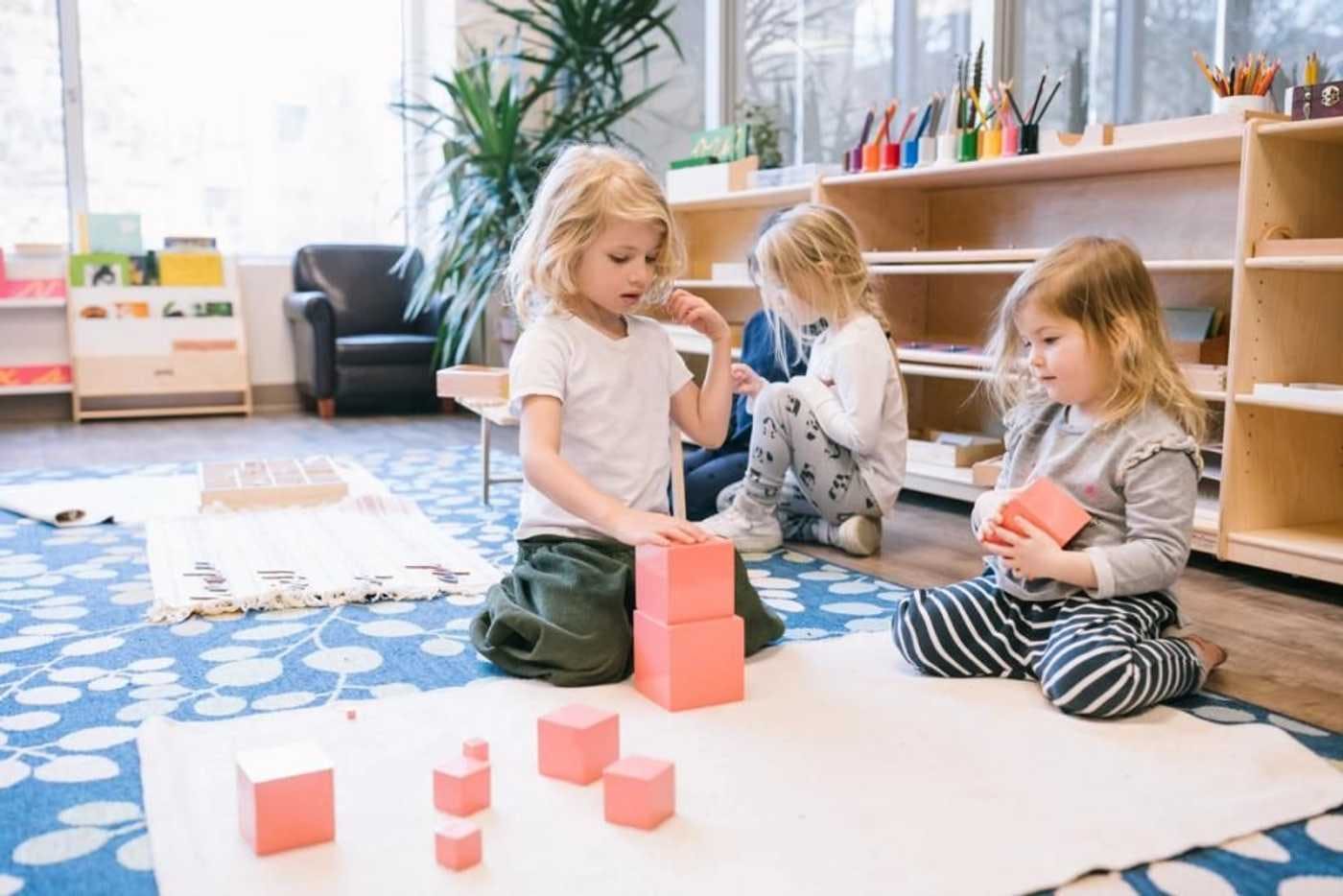 children sitting in montessori classroom on the floor playing with blocks