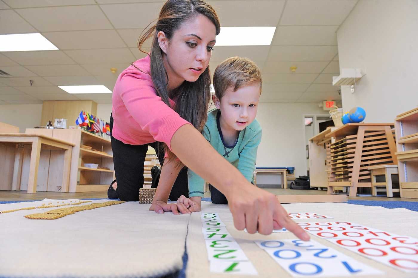 guide at guidepost montessori pointing to number with student
